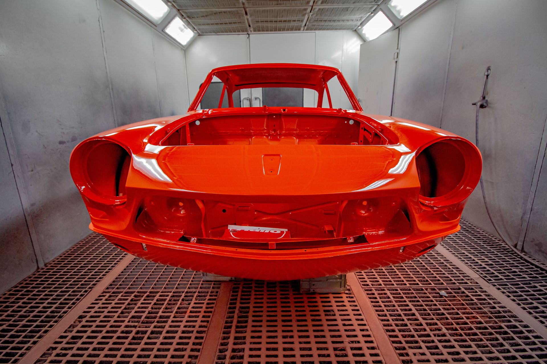 Vividly painted car body in a professional industrial spray paint booth.
